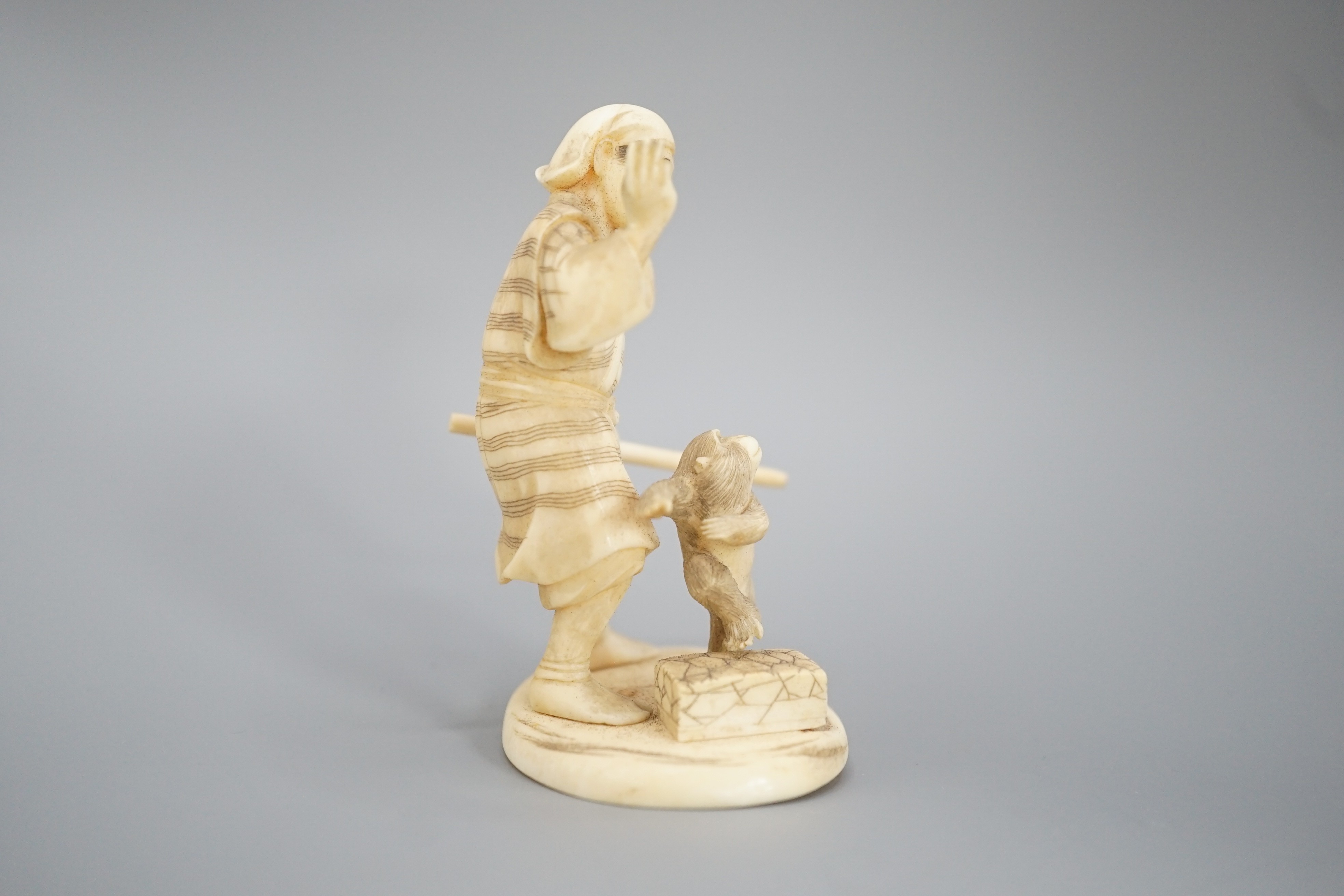 A Japanese ivory okimono of a monkey trainer, signed, Meiji period, 7.7 cm
